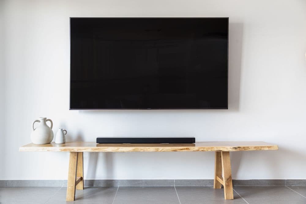 Flat-screen TV mounted on a wall above a media console, representative of the hardware myscreenverse runs on